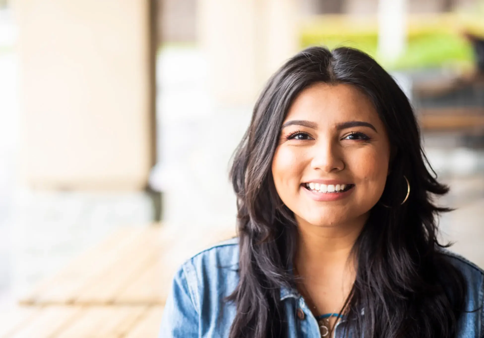 Smiling young woman in casual attire sitting indoors.